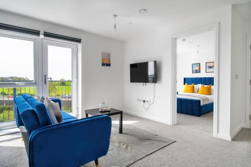 a living room with a blue couch and a bed at Brand New Luton Apartments in Luton