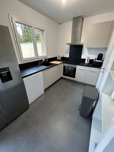 une grande cuisine avec des armoires blanches et une fenêtre dans l'établissement Maison de vacances, à Andernos-les-Bains