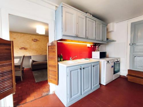 une cuisine avec des placards blancs et un mur rouge dans l'établissement LA MAISONNETTE, à Neuvy-Saint-Sépulchre