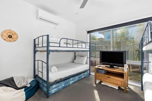 a room with two bunk beds and a television at Sunset Days Family Holiday House 200m to Shops in Ocean Grove
