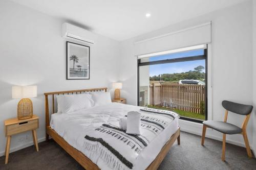 a bedroom with a bed and a chair and a window at Boardwalk on Bright Coastal Apartment in Torquay