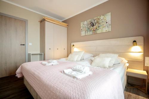 ミエンジズドロイェにあるBelMare by Baltic Homeのタオルが敷かれた白いベッドのある寝室