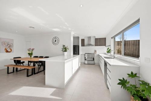 a white kitchen with a table and a dining room at All Day Sunshine and Relaxation -Pet friendly in Torquay