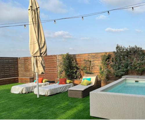 a patio with two chairs and an umbrella next to a pool at ADVA Boutique מלון אדווה in Bet Yannay