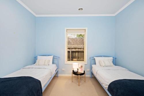 twee bedden in een kamer met blauwe muren bij Villa Avisa 5 minutes to the beach in Torquay