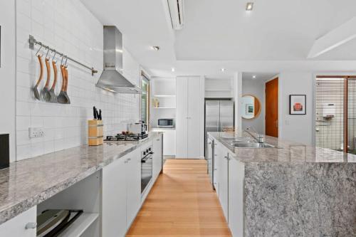 a kitchen with white counters and a wooden floor at Coastal Class and Sophistication 500m to Beach in Ocean Grove