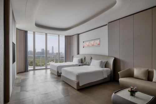 een hotelkamer met 2 bedden en een bank bij Vignette Collection The Xanadu Guangzhou, an IHG Hotel in Guangzhou