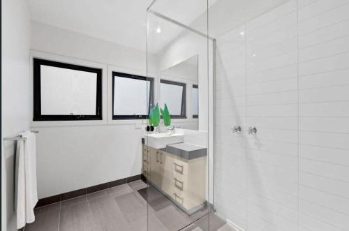 a white bathroom with a sink and a shower at Park View Coastal Oasis Barwon Heads Pet friendly in Barwon Heads