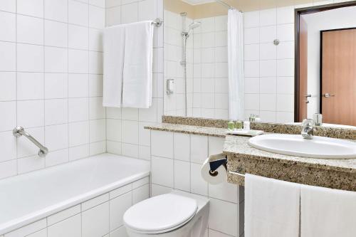 a white bathroom with a toilet and a sink at NH Mannheim Viernheim in Viernheim