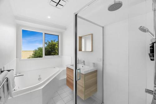 a white bathroom with a tub and a sink at Endless Dune Views Beach House in Ocean Grove