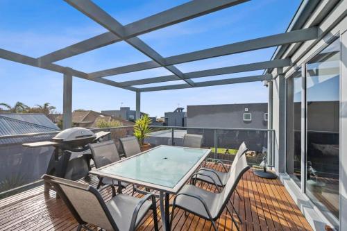 a patio with a glass table and chairs on a deck at Holiday Haven - Coastal Comfort in Old Torquay in Torquay