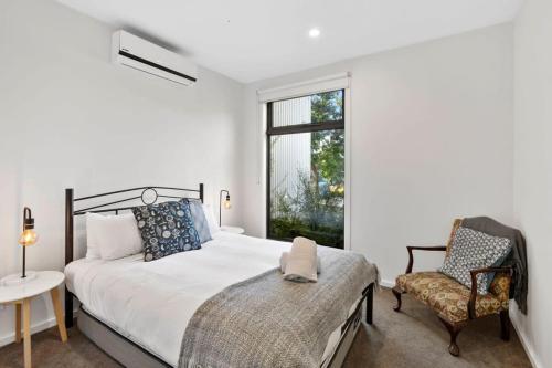 a bedroom with a bed and a chair and a window at Saltbush By The Park in Torquay