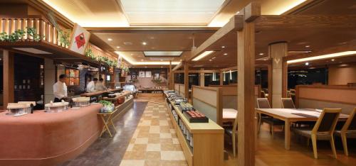 a restaurant with tables and chairs and a chef preparing food at Senri no Kaze in Tateyama