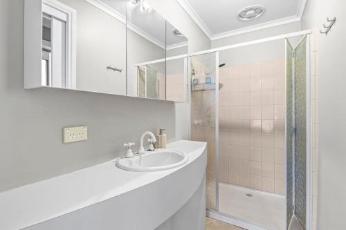 a white bathroom with a sink and a shower at Coastal Serenity Central Torquay in Torquay