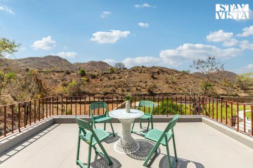 a patio with chairs and a table on a balcony at StayVista's Ikebana - Living By The Forest Edge - Mountain-view Villa with Infinity Pool, Lawn, & Indoor-Outdoor Games in Udaipur