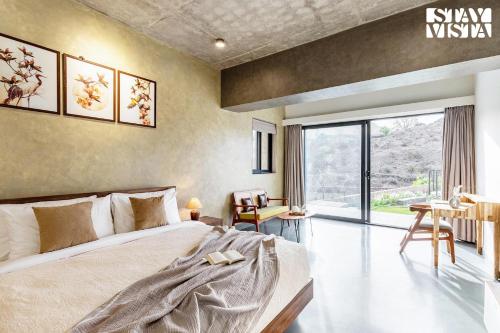 a bedroom with a bed and a large window at StayVista's Ikebana - Living By The Forest Edge - Mountain-view Villa with Infinity Pool, Lawn, & Indoor-Outdoor Games in Udaipur