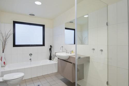 a white bathroom with a toilet and a sink and a tub at Seaview Sanctuary Jan Juc Distant Ocean View in Torquay