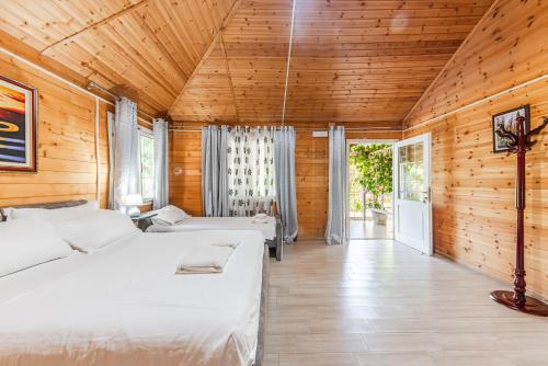 sypialnia z białymi łóżkami i drewnianymi ścianami w obiekcie Kompleksi Aljoma w mieście Fushë-Draç