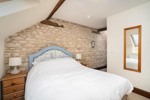 a bedroom with a white bed and a stone wall at The Granary self-catering cottage on a working farm in Buckinghamshire