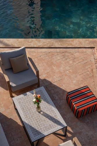 a patio with a table and a chair and a pool at Villa DAR BOUMA in Ghazoua