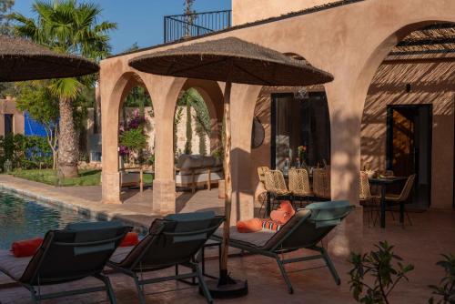 a patio with chairs and umbrellas next to a pool at Villa DAR BOUMA in Ghazoua