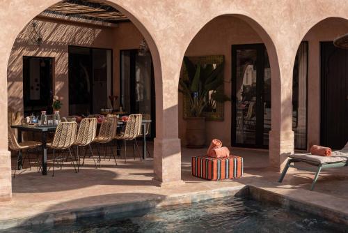 a patio with a table and chairs and a pool of water at Villa DAR BOUMA in Ghazoua