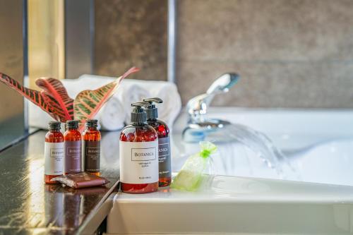 a bathroom counter with three bottles of alcohol next to a sink at Hotel President in Budapest
