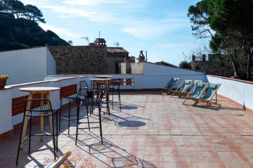 un groupe de chaises assises autour d'un bar sur un toit dans l'établissement Hostal Boutique Es Menut, à Tossa de Mar