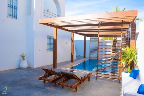 a patio with two chairs and a swimming pool at DAR AMEL in Houmt Souk