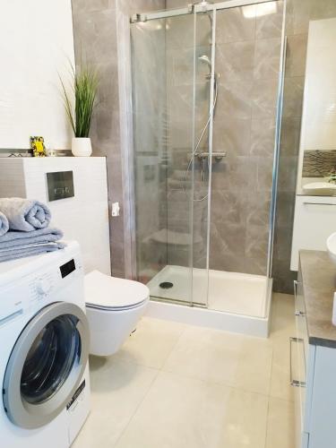 a bathroom with a shower and a washing machine at Ukiel Park J&J in Olsztyn