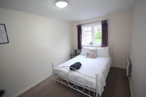 1 dormitorio con 1 cama blanca y ventana en Colham Place, en Hillingdon