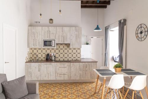 カディスにあるLevante by Gades Gestiónの白いキャビネット、テーブルと椅子付きのキッチンが備わります。