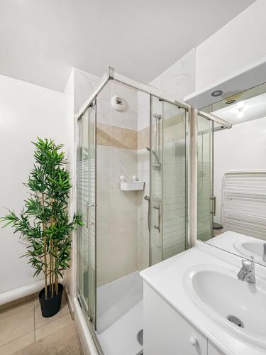 une salle de bain avec une douche en verre et un lavabo dans l'établissement Sérénité Urbaine Aubervilliers, à Aubervilliers