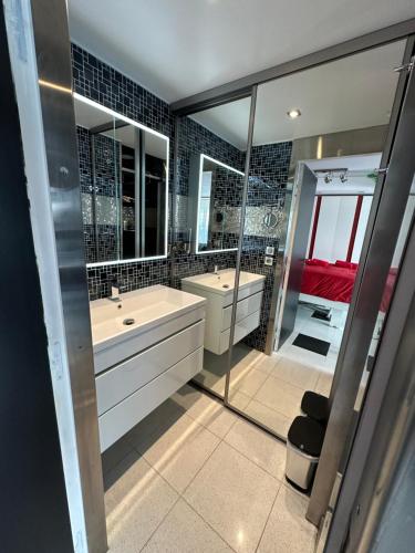 une salle de bain avec deux lavabos et un grand miroir dans l'établissement JOIA PARIS - MOISANT, à Paris