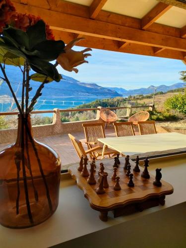 a table with a chess board and a vase with a flower at Le Panoramique du Plongeoir - T4 spacieux de 90m2 avec grande terrasse vue sur le lac de Serre Ponçon in Savines