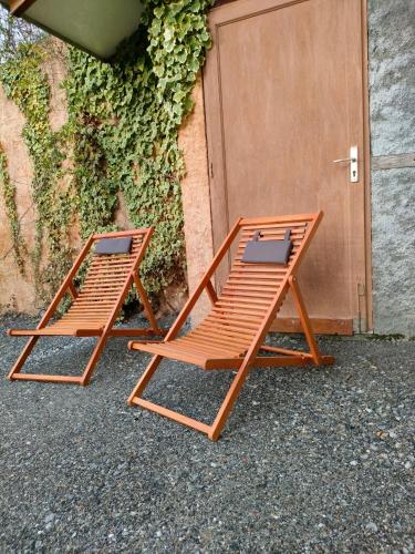 two wooden lounge chairs sitting next to a door at Le Panoramique du Plongeoir - T4 spacieux de 90m2 avec grande terrasse vue sur le lac de Serre Ponçon in Savines