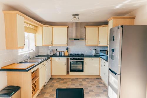 a kitchen with white cabinets and a refrigerator at Remarkable 4-Bed House in Cardiff in Cardiff