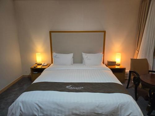Yeosu Narsha Hotel في يوسو: غرفة فندقية بسرير كبير فيها مصباحين