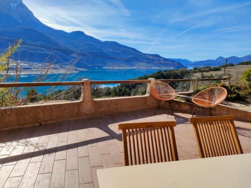 a table and chairs on a balcony with a view of a mountain at Le Panoramique du Plongeoir - T4 spacieux de 90m2 avec grande terrasse vue sur le lac de Serre Ponçon in Savines
