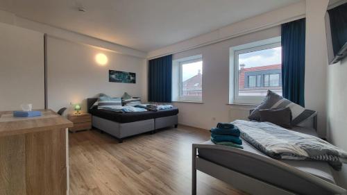 a bedroom with a bed and a couch and two windows at Boardinghouse Heilbronn in Heilbronn