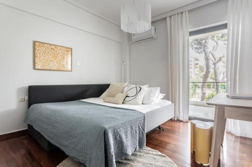 ein Schlafzimmer mit einem Bett und einem großen Fenster in der Unterkunft Chic & Luminous 3BR Apartment in Kifisia by UPSTREET in Athen