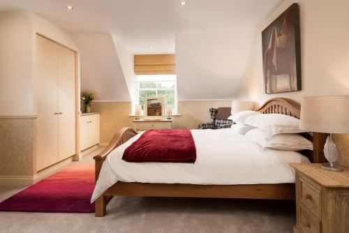 a bedroom with a large bed with a red blanket at Dryburgh Steading Four in Saint Boswells