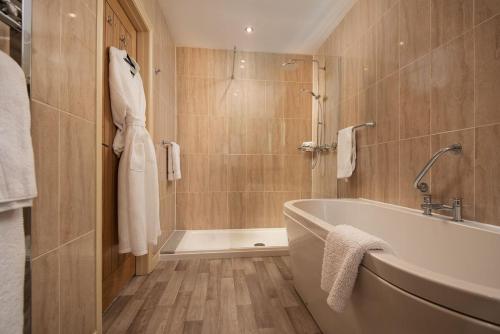 a bathroom with a tub and a shower at Dryburgh Steading Four in Saint Boswells