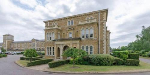 een groot bakstenen gebouw met struiken ervoor bij Stunning-Gated-Listed Stay-Park-Homestay-Retreat in Londen