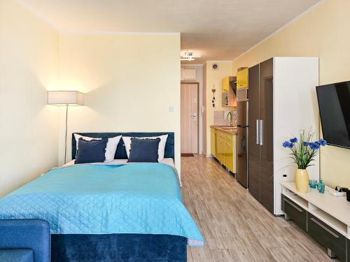 1 dormitorio con 1 cama azul y TV en visit baltic - Monte Cassino, en Świnoujście