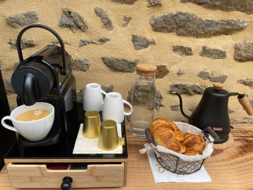 a table with a cup of coffee and a basket of bread at Villa Lily Spa, chambre d’hôtes avec spa privatif in La Vicomté-sur-Rance