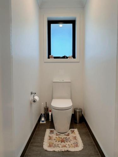 a bathroom with a toilet with a window and a rug at Bunny Riveting House at Granton in Grantow