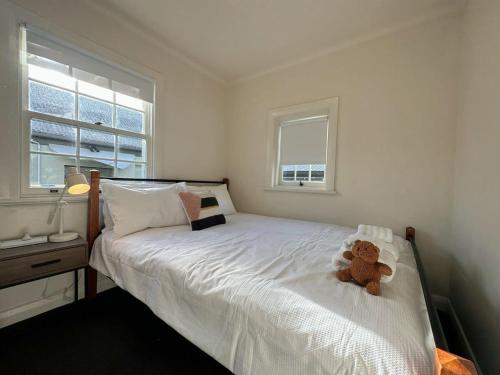 a teddy bear sitting on a bed in a bedroom at Hobart City Oasis with 3 beds in Hobart