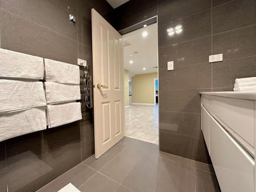 ein Bad mit einer weißen Tür und Handtüchern in der Unterkunft City Retreat for 8 with Spacious Rooms in Hobart