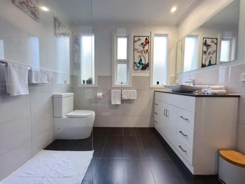 a white bathroom with a toilet and a sink at Fonton Blue Holiday Home close to City and Airport in Moonah